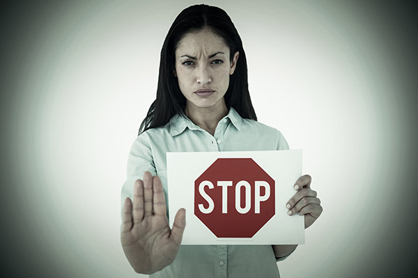 frowning woman with hand held up and holding stop sign